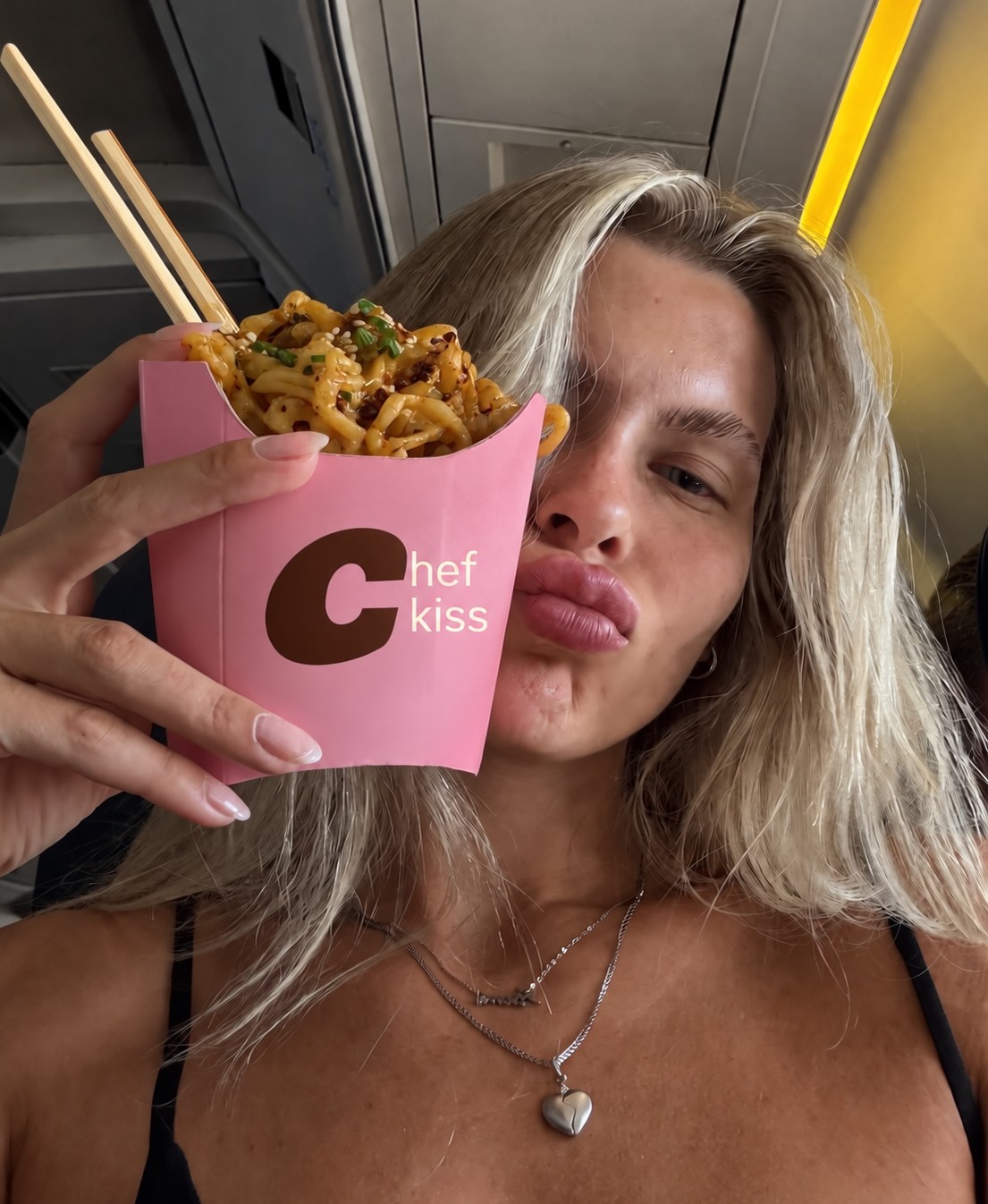 Woman holding a pink Cheap Noodles cup