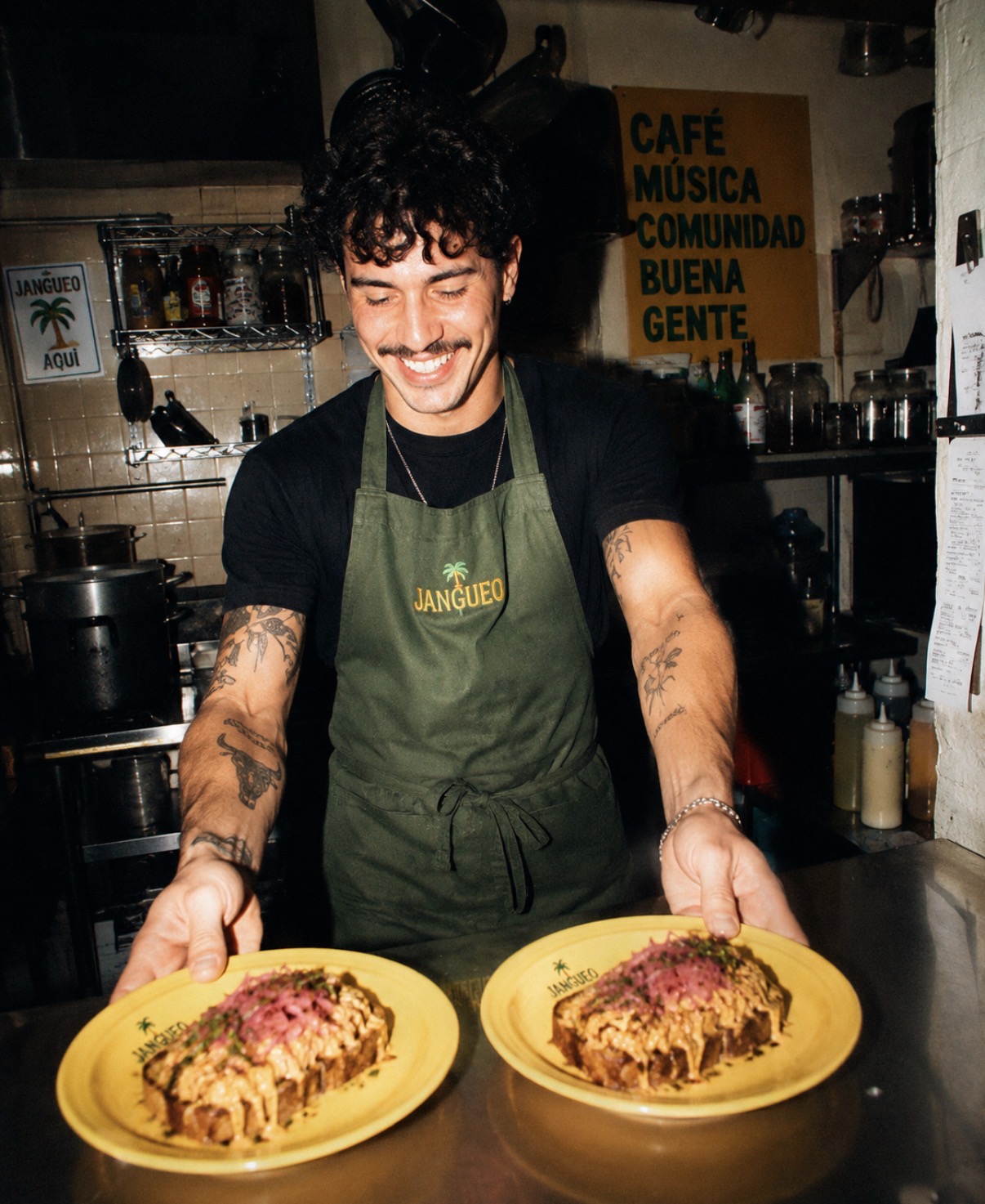 Chef in a Jangueo apron holding two plates