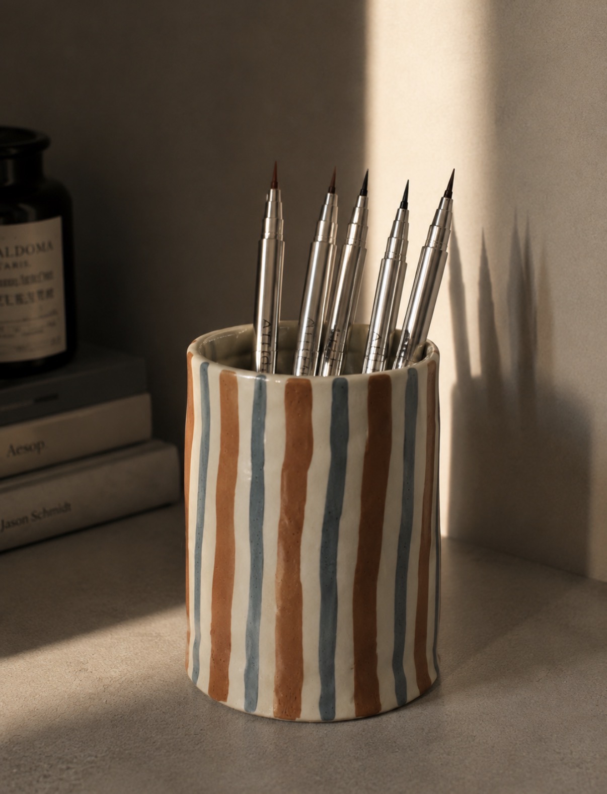 Antiq brushes in a striped ceramic cup